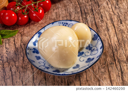 Scamorza cheese in bowl with cherry tomatoes on wooden background Scamorza cheese in bowl with cherry tomatoes on wooden background 142460200