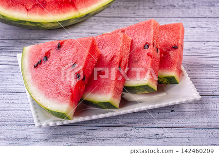 Juicy red watermelon slices on white plate on rustic wooden background Juicy red watermelon slices on white plate on rustic wooden background 142460209