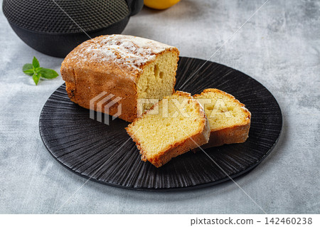 Pound cake with powdered sugar on black plate, sliced to show moist crumb texture Pound cake with powdered sugar on black plate, sliced to show moist crumb texture 142460238