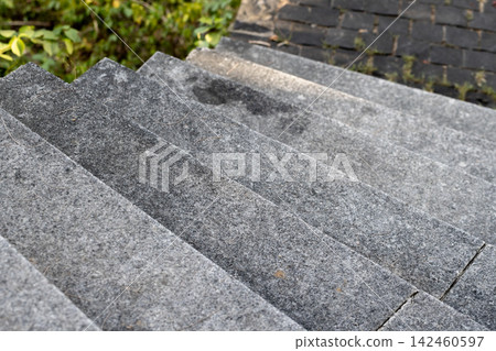Granite outdoor steps descend toward a paved garden walkway Granite outdoor steps descend toward a paved garden walkway 142460597