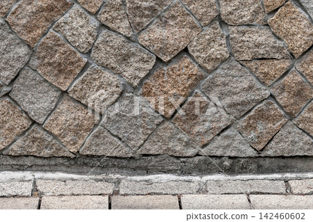 Rough granite cobblestone wall with diagonal block pattern Rough granite cobblestone wall with diagonal block pattern 142460602