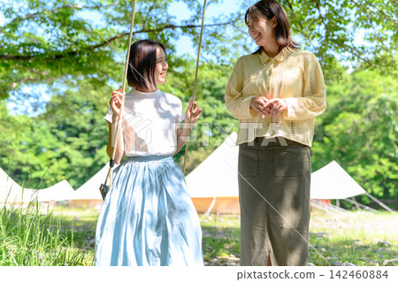 一位女士正在和盪鞦韆的女孩說話。 一位女士正在和盪鞦韆的女孩說話。 142460884