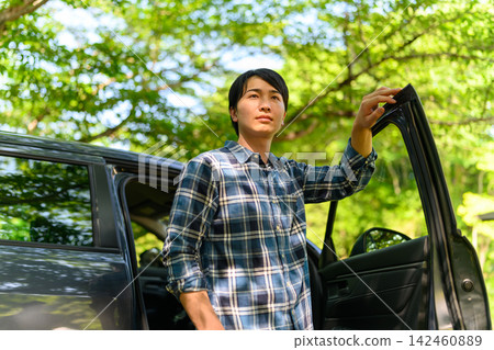 夏日斑駁的陽光下,一名男子打開車門。 夏日斑駁的陽光下,一名男子打開車門。 142460889