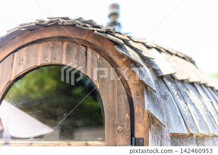 Round windows and roof of a wooden dome-shaped hut 142460953