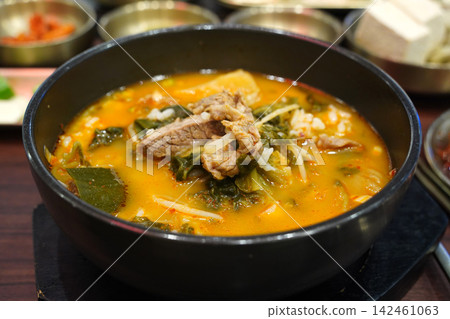Spicy Korean beef soup with radish and napa cabbage served sizzling hot in a traditional black earthenware bowl ttukbaegi close-up Spicy Korean beef soup with radish and napa cabbage served sizzling hot in a traditional black earthenware bowl ttukbaegi close-up 142461063