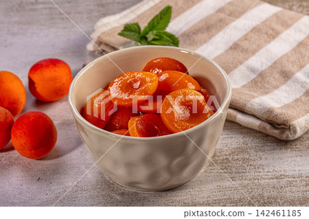 Bowl of sliced apricots with whole fruits and mint on rustic surface Bowl of sliced apricots with whole fruits and mint on rustic surface 142461185