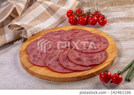 Sliced deli meat on wooden board with cherry tomatoes and kitchen towel Sliced deli meat on wooden board with cherry tomatoes and kitchen towel 142461186