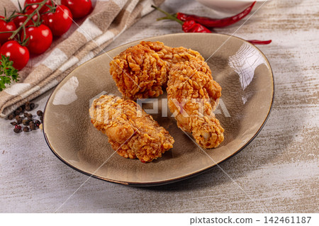 Crispy fried chicken pieces on rustic plate with cherry tomatoes and red chili peppers Crispy fried chicken pieces on rustic plate with cherry tomatoes and red chili peppers 142461187