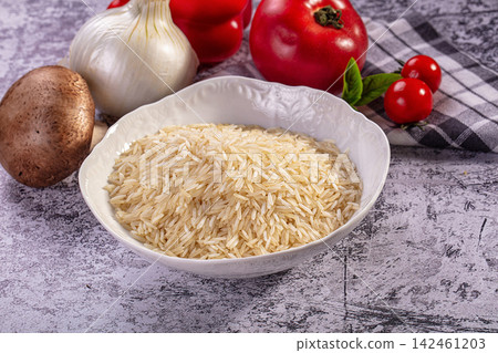 Bowl of uncooked rice with fresh vegetables on rustic surface Bowl of uncooked rice with fresh vegetables on rustic surface 142461203