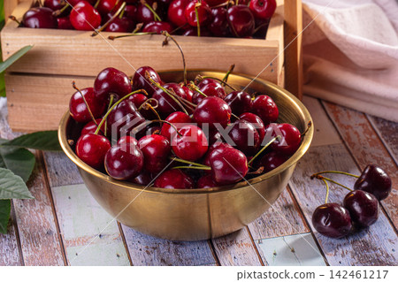 Fresh red cherries in brass bowl on rustic wooden table Fresh red cherries in brass bowl on rustic wooden table 142461217