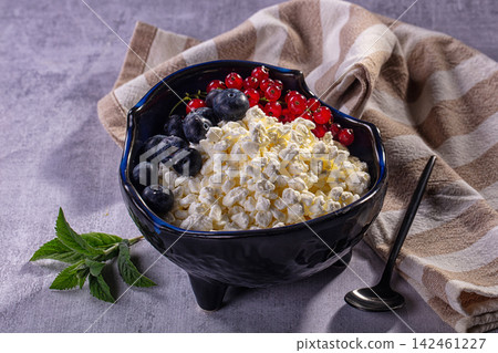 Cottage cheese bowl with blueberries and red currants on textured surface Cottage cheese bowl with blueberries and red currants on textured surface 142461227