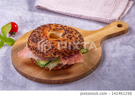 Seeded bagel sandwich with smoked salmon cucumber and lettuce on wooden board Seeded bagel sandwich with smoked salmon cucumber and lettuce on wooden board 142461298