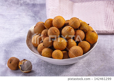 Bowl of fresh longan fruit with one peeled showing translucent flesh Bowl of fresh longan fruit with one peeled showing translucent flesh 142461299