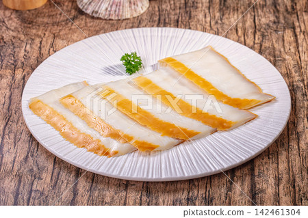 Smoked squid fillet slices served on white textured plate over rustic wooden background Smoked squid fillet slices served on white textured plate over rustic wooden background 142461304