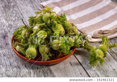 Fresh green hazelnuts or cobnuts in wooden bowl on rustic table Fresh green hazelnuts or cobnuts in wooden bowl on rustic table 142461321