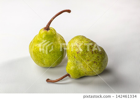 Two green pears with speckled skin on white textured surface 142461334