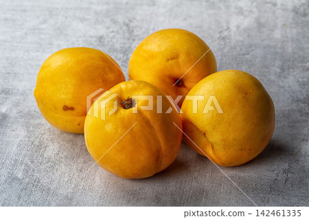 Four yellow nectarines arranged on textured gray surface Four yellow nectarines arranged on textured gray surface 142461335