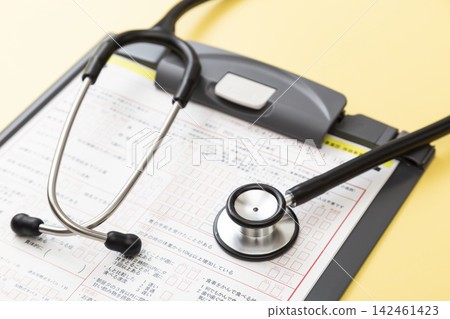 A medical questionnaire and stethoscope on a yellow background. A medical questionnaire and stethoscope on a yellow background. 142461423