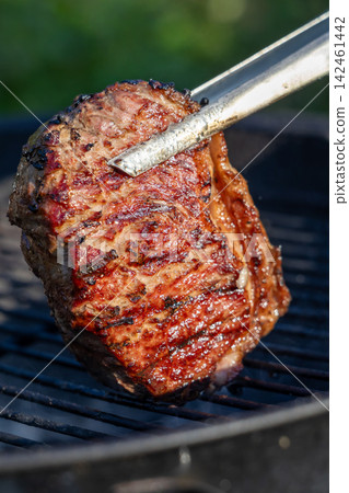 Beef Steak Grilling on Charcoal Barbecue in Backyard Garden Beef Steak Grilling on Charcoal Barbecue in Backyard Garden 142461442