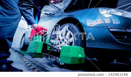 Car mechanic installing sensor during suspension adjustment. Car mechanic installing sensor during suspension adjustment. 142461546