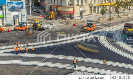 Asphalt paver, roller and truck on the road repair site during asphalting timelapse. Road construction equipment. Asphalt paver, roller and truck on the road repair site during asphalting timelapse. Road construction equipment. 142461936
