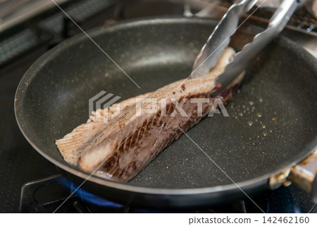 Cooking process: searing the surface of bonito in a frying pan. Homemade seared bonito. Cooking process: searing the surface of bonito in a frying pan. Homemade seared bonito. 142462160