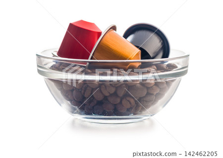 Colorful Coffee Capsules Nestled in Glass Bowl Filled With Roasted Coffee Beans on White Background Colorful Coffee Capsules Nestled in Glass Bowl Filled With Roasted Coffee Beans on White Background 142462205