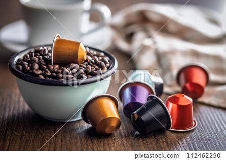 Colorful Espresso Capsules and Coffee Beans in Bowl with Cup on Rustic Wooden Table 142462290