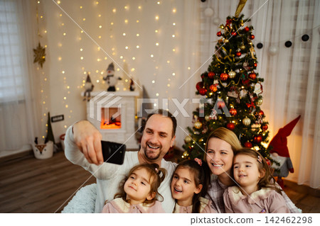 Family taking Christmas selfie with smartphone at home Family taking Christmas selfie with smartphone at home 142462298