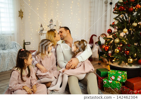 Family celebrating Christmas together in living room with tree and gifts Family celebrating Christmas together in living room with tree and gifts 142462304