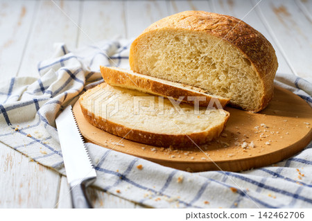Round loaf of wheat rustic bread with sourdough on white table, selective focus. Round loaf of wheat rustic bread with sourdough on white table, selective focus. 142462706