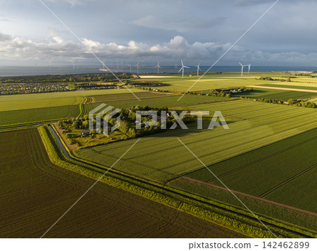 High angle wide horizontal aerial drone photograph of polder fields, farmhouse, wind turbines, storm barrier, and sea in Neeltje Jans, Zeeland, Netherlands in warm golden hour summer light High angle wide horizontal aerial drone photograph of polder fields, farmhouse, wind turbines, storm barrier, and sea in Neeltje Jans, Zeeland, Netherlands in warm golden hour summer light 142462899
