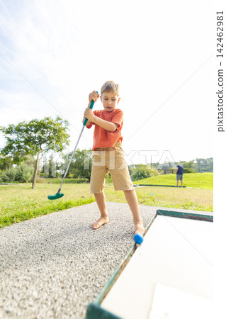 Young boy playing mini golf on summer vacation Young boy playing mini golf on summer vacation 142462981