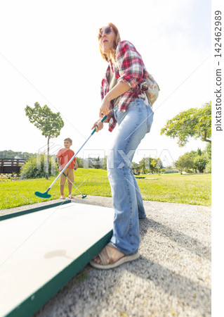 Mother and son playing mini golf outdoors 142462989
