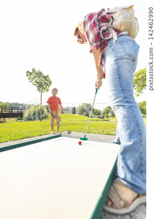 Mother and child playing miniature golf together Mother and child playing miniature golf together 142462990