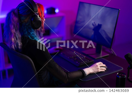 Young woman gaming in a colorful room with modern equipment 142463089
