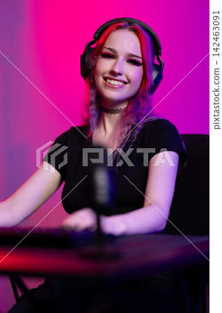 Young woman gaming with headphones and microphone in colorful lighting Young woman gaming with headphones and microphone in colorful lighting 142463091