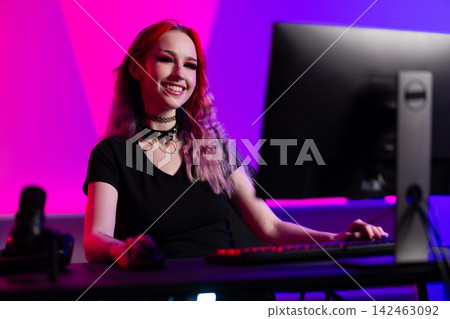Young female streamer gaming with vibrant lighting in a modern setup 142463092