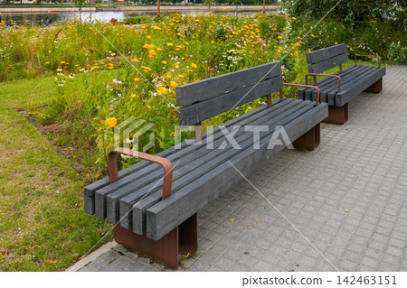 Modern Wooden Benches Beside Colorful Greenery in Landscaped Urban City Riverside Public Space Modern Wooden Benches Beside Colorful Greenery in Landscaped Urban City Riverside Public Space 142463151