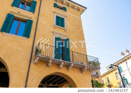 Yellow Italian Building Facade with Green Shutters and Balcony on a Clear Day in Verona, Italy 142463237