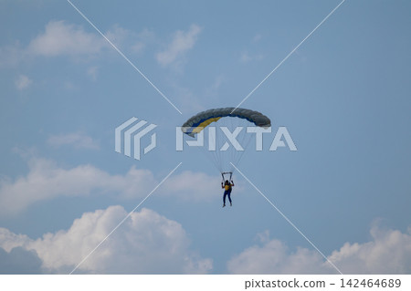 Parachutist with yellow blue parachute in clouds Parachutist with yellow blue parachute in clouds 142464689