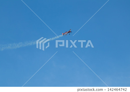 Red stunt airplane with contrails in blue sky Red stunt airplane with contrails in blue sky 142464742