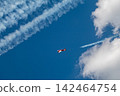 Light red plane in clouds with contrails 142464754