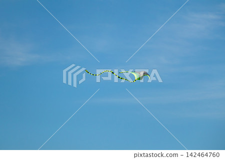 Kite flying under bright sun and clouds Kite flying under bright sun and clouds 142464760