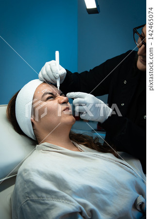 Doctor drawing guide marks around patient's eyebrows Doctor drawing guide marks around patient's eyebrows 142465074
