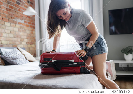 Happy Woman Packing Suitcase In Room For Upcoming Travel Preparing For A Holiday Journey Happy Woman Packing Suitcase In Room For Upcoming Travel Preparing For A Holiday Journey 142465350