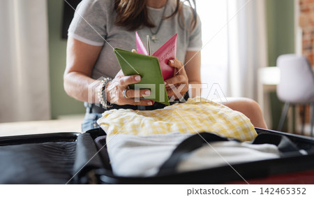 Woman Getting Ready For A Holiday Trip, Reviewing Passport And Visa Details Woman Getting Ready For A Holiday Trip, Reviewing Passport And Visa Details 142465352
