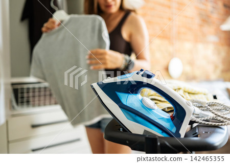 Girl Hanging Ironed T-Shirt In Wardrobe Ironing Freshly Washed Clothes At Home 142465355