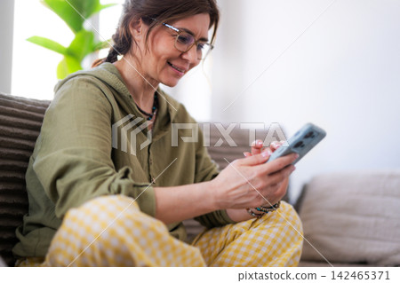 Young Woman At Home Browsing Social Media Feed On Smartphone Surfing The Internet Young Woman At Home Browsing Social Media Feed On Smartphone Surfing The Internet 142465371