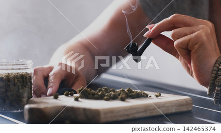 Girl Lights A Smoking Pipe With Dry CBD Cannabis And Smokes It With Thick Smoke For Calmness Of The Nervous System Girl Lights A Smoking Pipe With Dry CBD Cannabis And Smokes It With Thick Smoke For Calmness Of The Nervous System 142465374